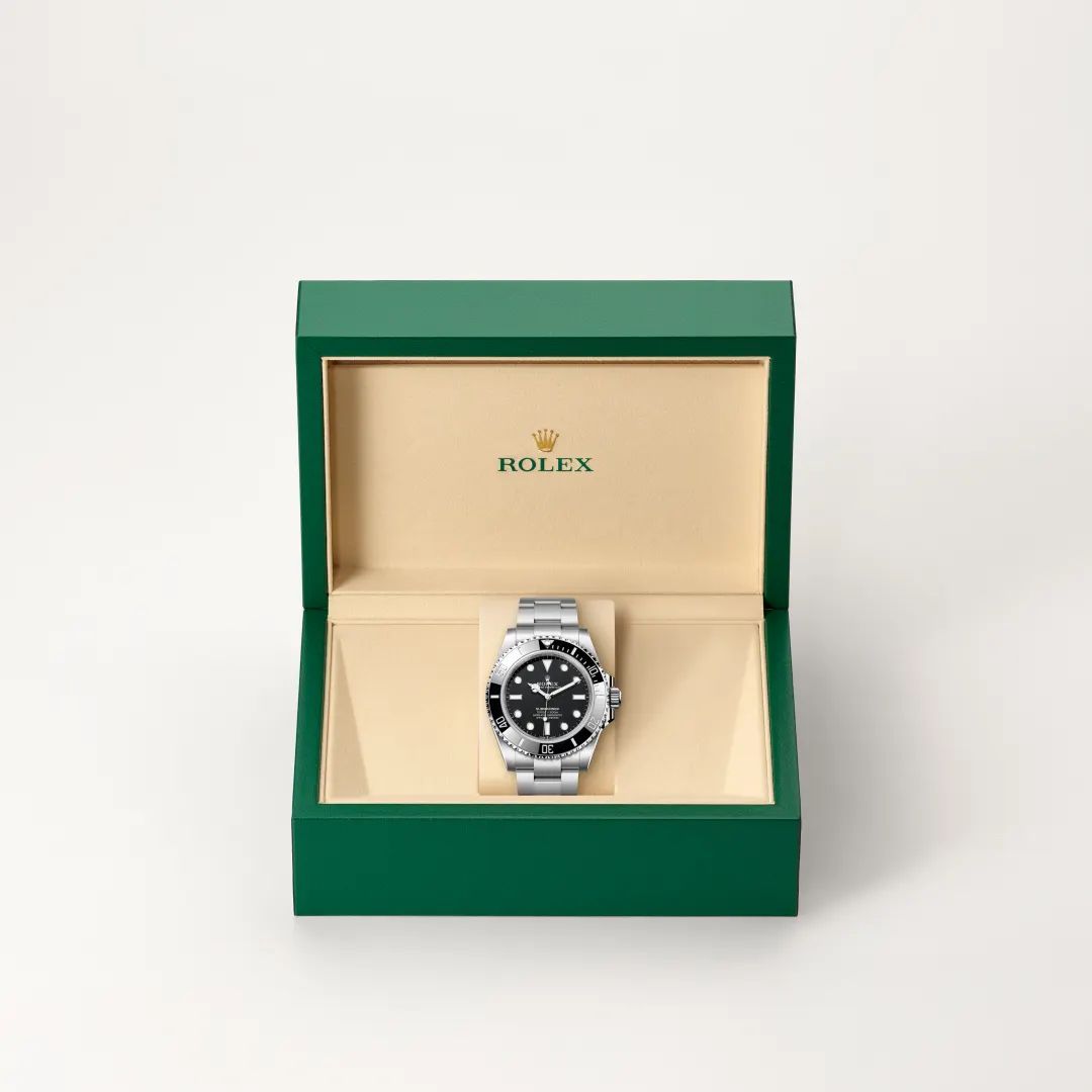 Stainless steel Rolex watch in an open green presentation box with a beige interior and logo inside lid. | Brela