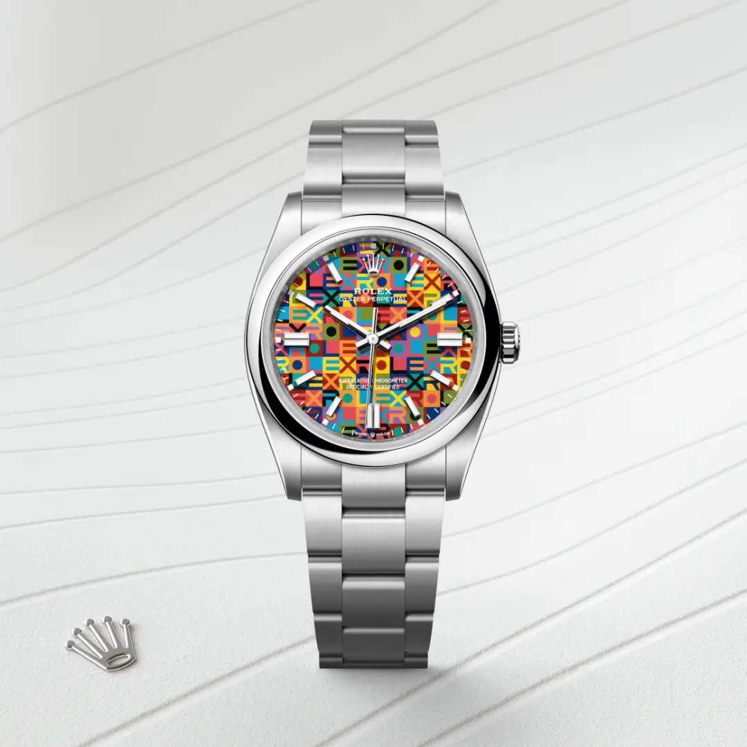 m126000-0016-slide1 | Brela Stainless steel Rolex Oyster Perpetual watch with a bright mosaic dial, placed on a light striped surface; Rolex crown logo charm visible nearby. | Brela