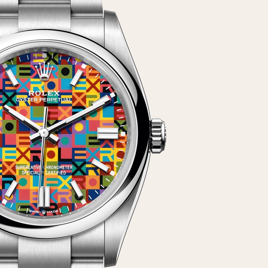 m126000-0016-slide3 | Brela Close-up of a stainless steel Rolex Oyster Perpetual watch with a colorful mosaic dial and silver hands on a light background. | Brela