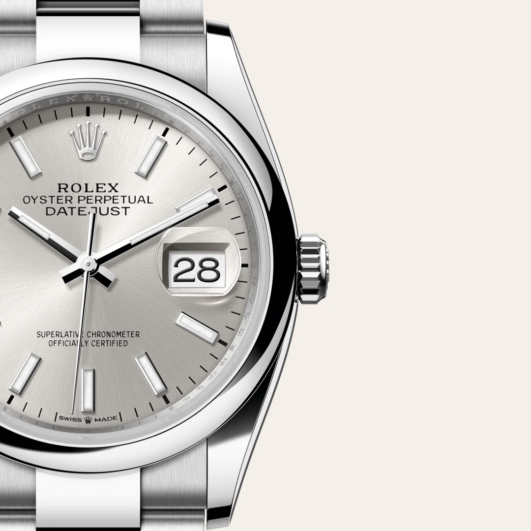 Close-up of a silver Rolex Datejust wristwatch showing the date window reading 28, with a polished bezel and brushed metal bracelet. | Brela