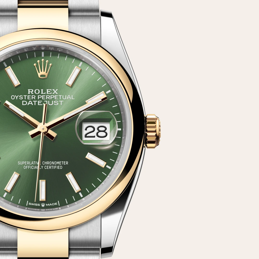 Close-up of a two-tone Rolex Oyster Perpetual Datejust watch with a green dial, gold bezel, and date window showing 28. | Brela