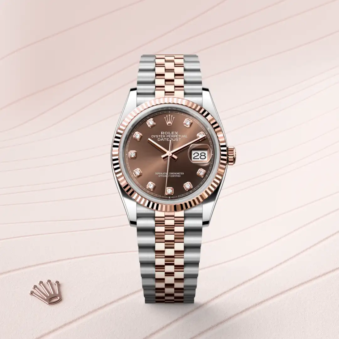 Rolex Datejust two-tone wristwatch with a brown dial, diamond hour markers, and a two-tone Jubilee bracelet on a pale pink background. | Brela