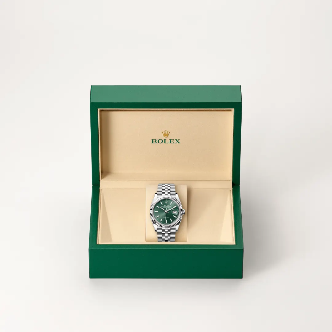 Rolex stainless steel watch with a green dial displayed in an open green presentation box with a beige interior. | Brela