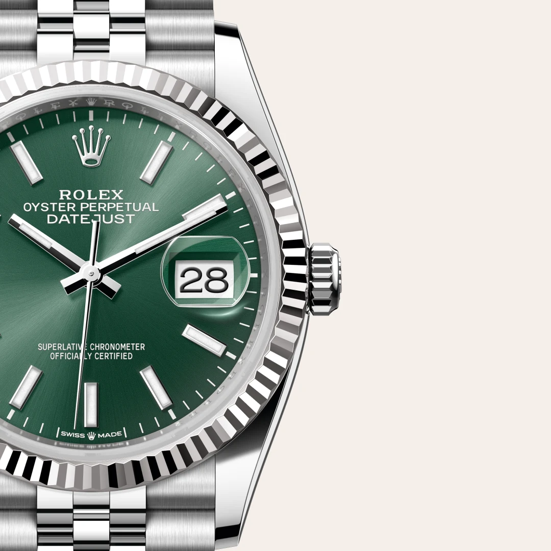 Close-up of a Rolex Oyster Perpetual Datejust wristwatch with a green dial, date window showing 28, and a silver fluted bezel and bracelet. | Brela