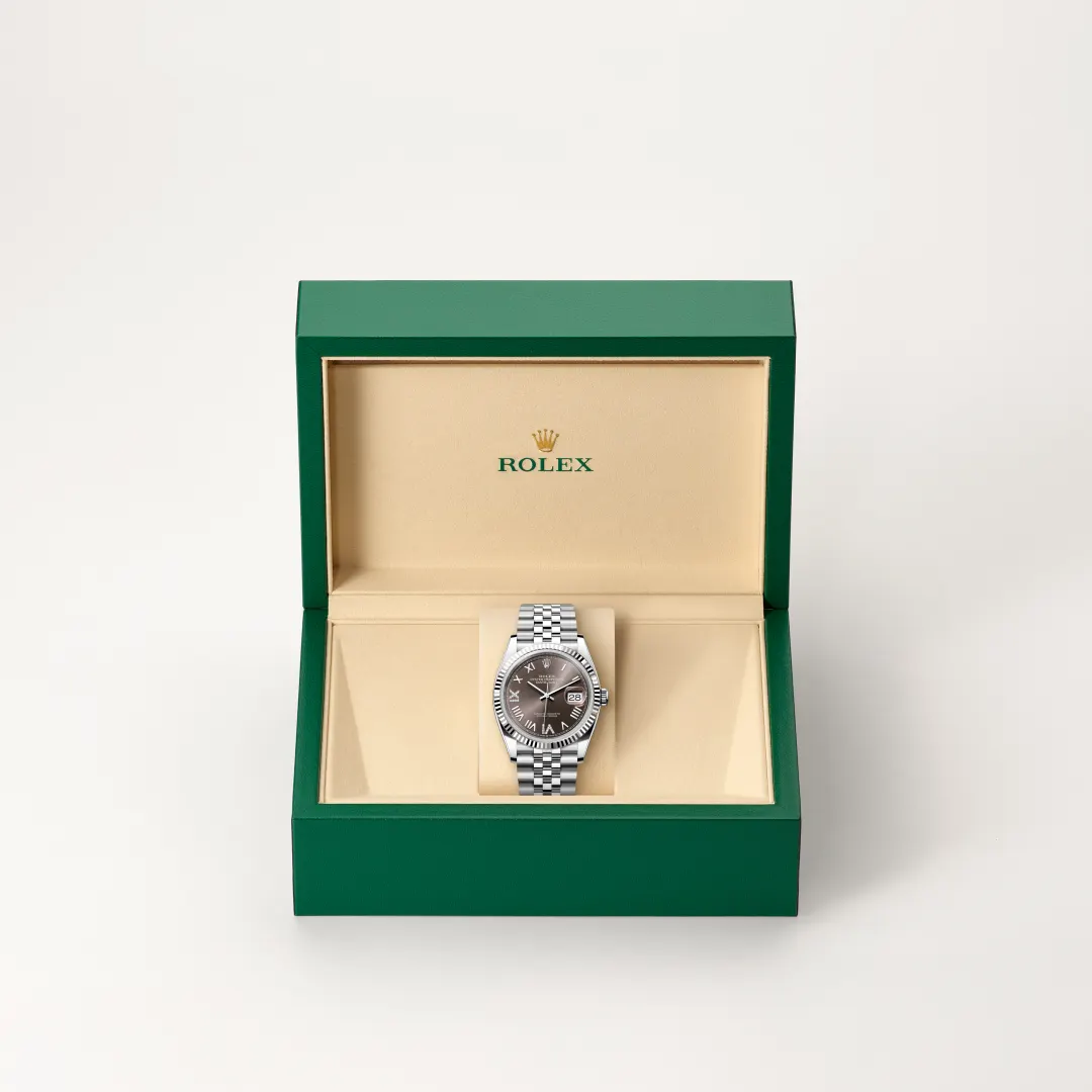 Rolex wristwatch displayed in an open green presentation box with a beige interior. | Brela