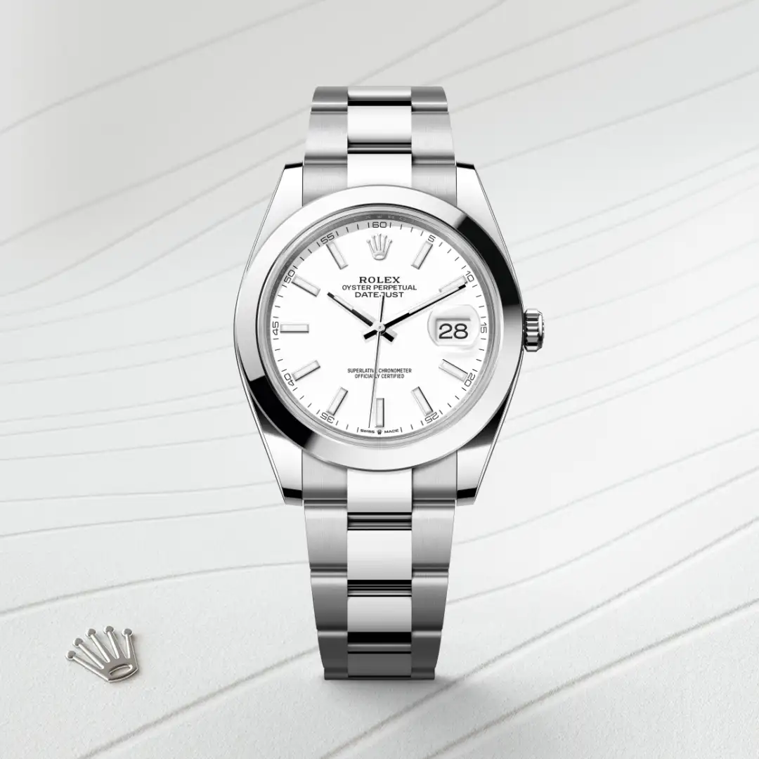 Stainless steel Rolex Datejust wristwatch with a white dial and date window at 3 o'clock, resting on a light striped surface with the Rolex crown emblem nearby. | Brela