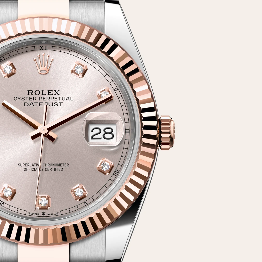 m126331-0007-slide3 | Brela Close-up of a Rolex Oyster Perpetual Datejust watch with a rose gold fluted bezel, pink dial, diamond hour markers, and a date window showing 28. | Brela
