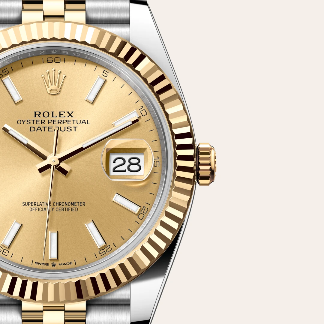 Close-up of a gold Rolex Datejust watch with fluted bezel, champagne dial, and date window at 3 o'clock, two-tone bracelet visible. | Brela