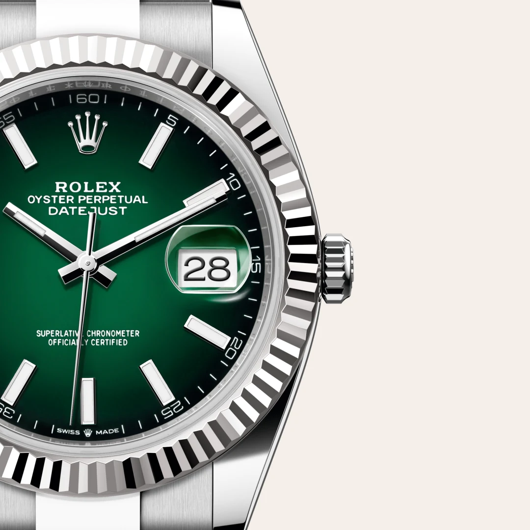 Close-up of a Rolex Datejust watch with a green dial, date window at 3 o'clock, and a fluted bezel. | Brela