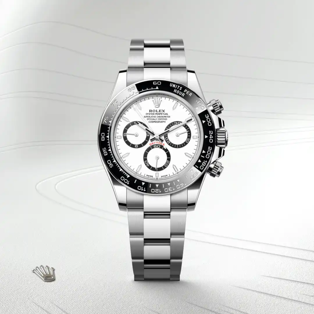 m126500ln-0001-slide1 | Brela Close-up of a stainless steel Rolex Daytona chronograph watch with a white dial and black tachymeter bezel on a light background. | Brela
