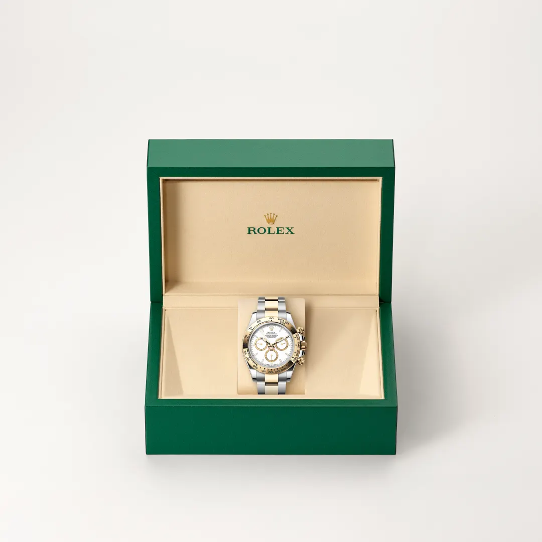 Rolex wristwatch with silver and gold bracelet on a beige display cushion inside a green presentation box
