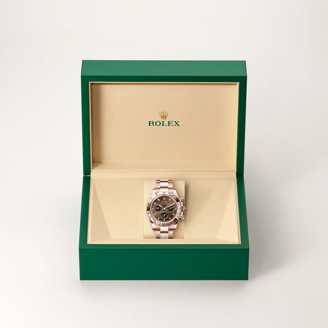 Rose gold Rolex watch in an open green box with beige interior, the brand name visible inside lid.