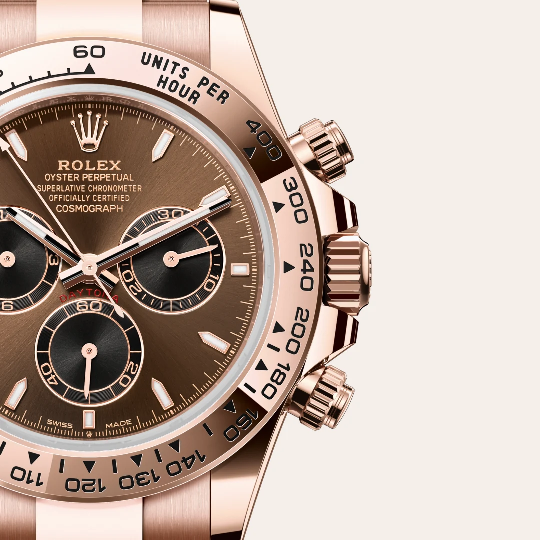 Close-up of a rose-gold Rolex Daytona watch with a brown dial, three subdials, and a tachymeter bezel showing unit markings.