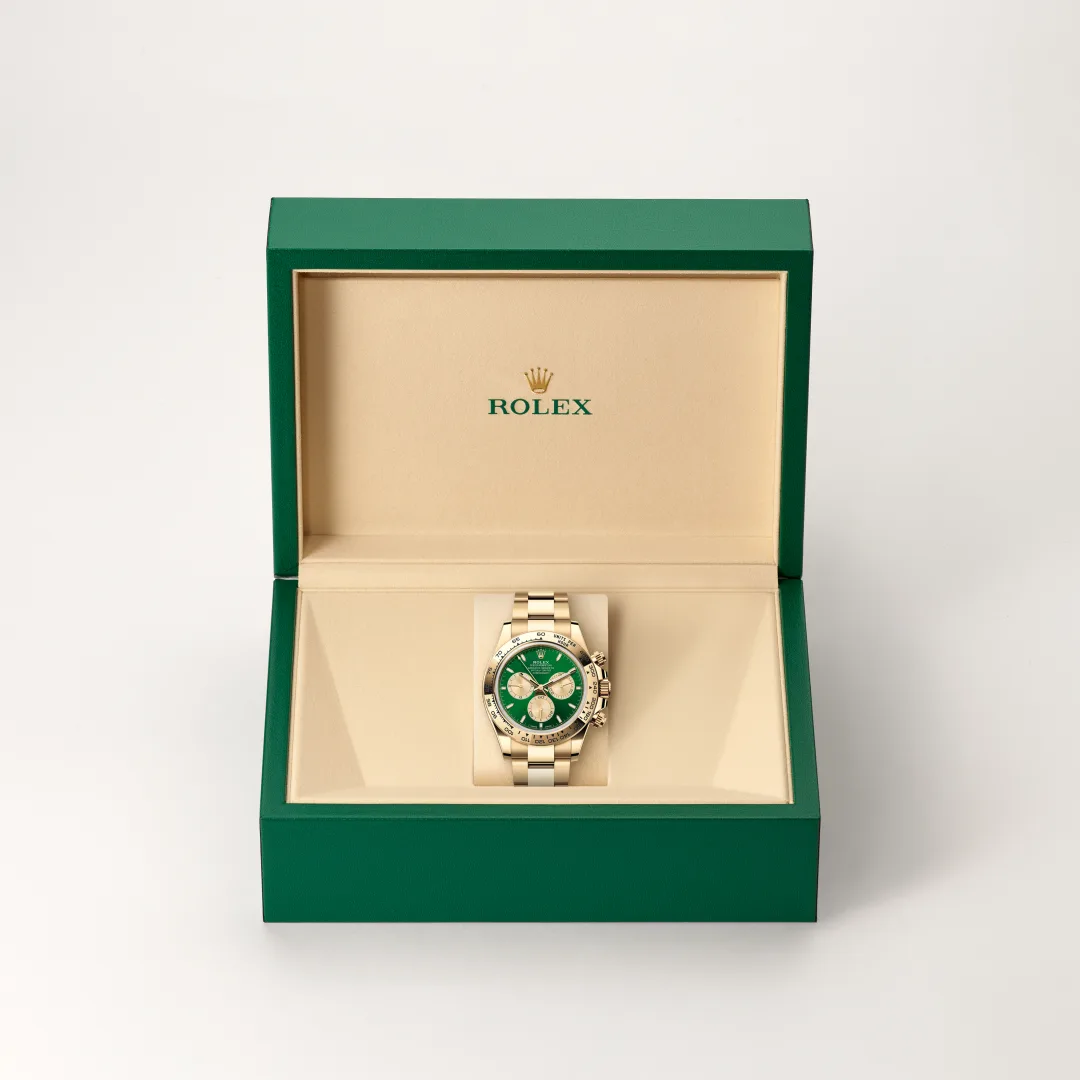 m126508-0008-slide2 | Brela Rolex watch with green dial and gold bracelet in an open green box with beige interior labeled Rolex in gold. | Brela