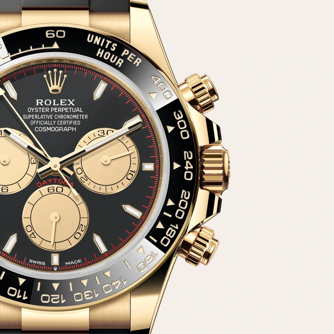 Close-up of a gold Rolex Daytona watch with a black dial, gold subdials, and a black tachymeter bezel. | Brela