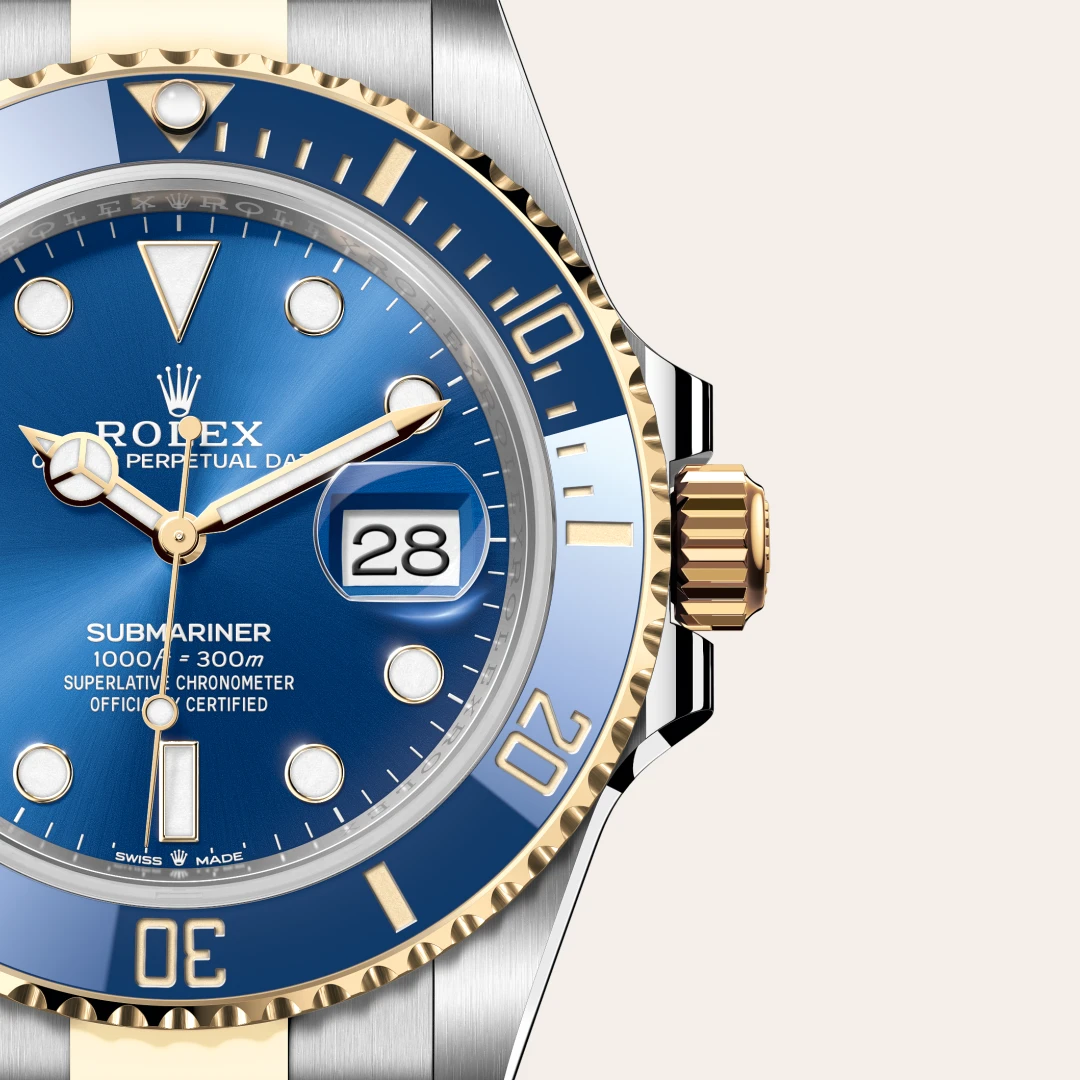 m126613lb-0002-slide3 | Brela Close-up of a two-tone Rolex Submariner with blue dial, gold bezel, and date window magnifier showing 28. | Brela