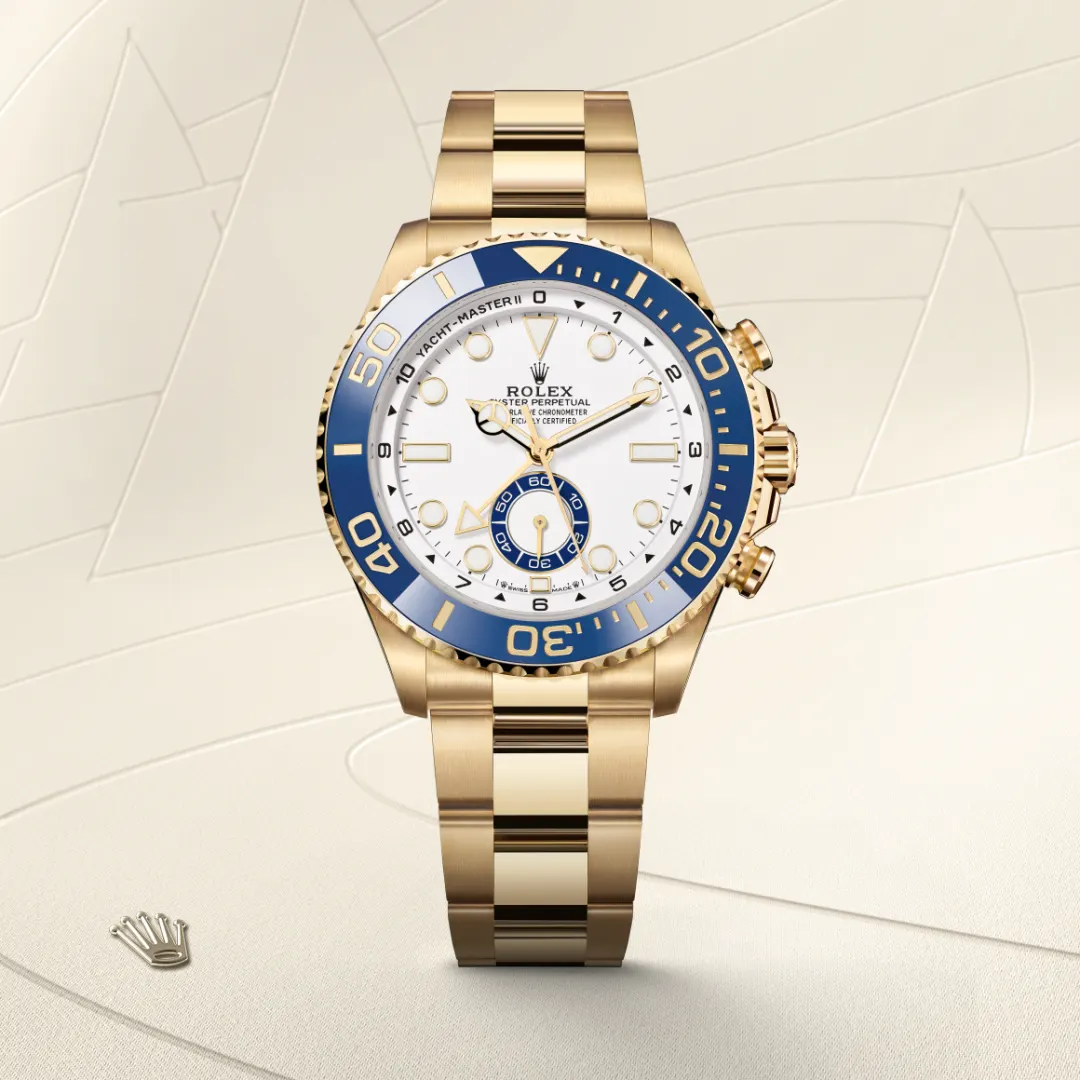 Gold Rolex wristwatch with a white dial and blue bezel on a pale beige backdrop.