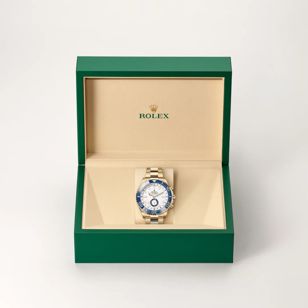 Rolex watch in an open green box with beige interior, gold band and blue-bezel face showing the timepiece craftsmanship