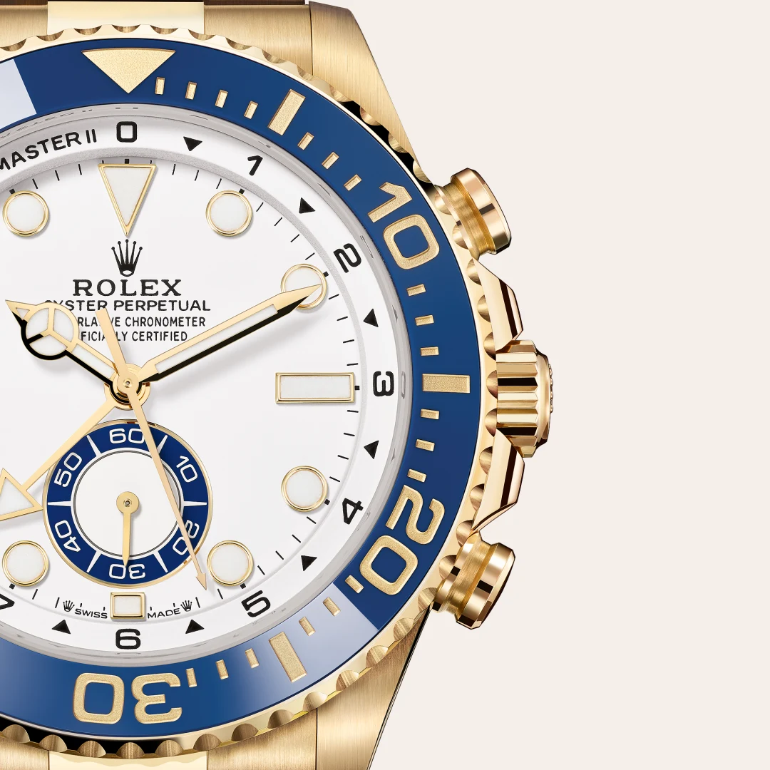 Close-up of a gold Rolex GMT-Master II watch with a white dial, blue and gold bezel, and gold hands.