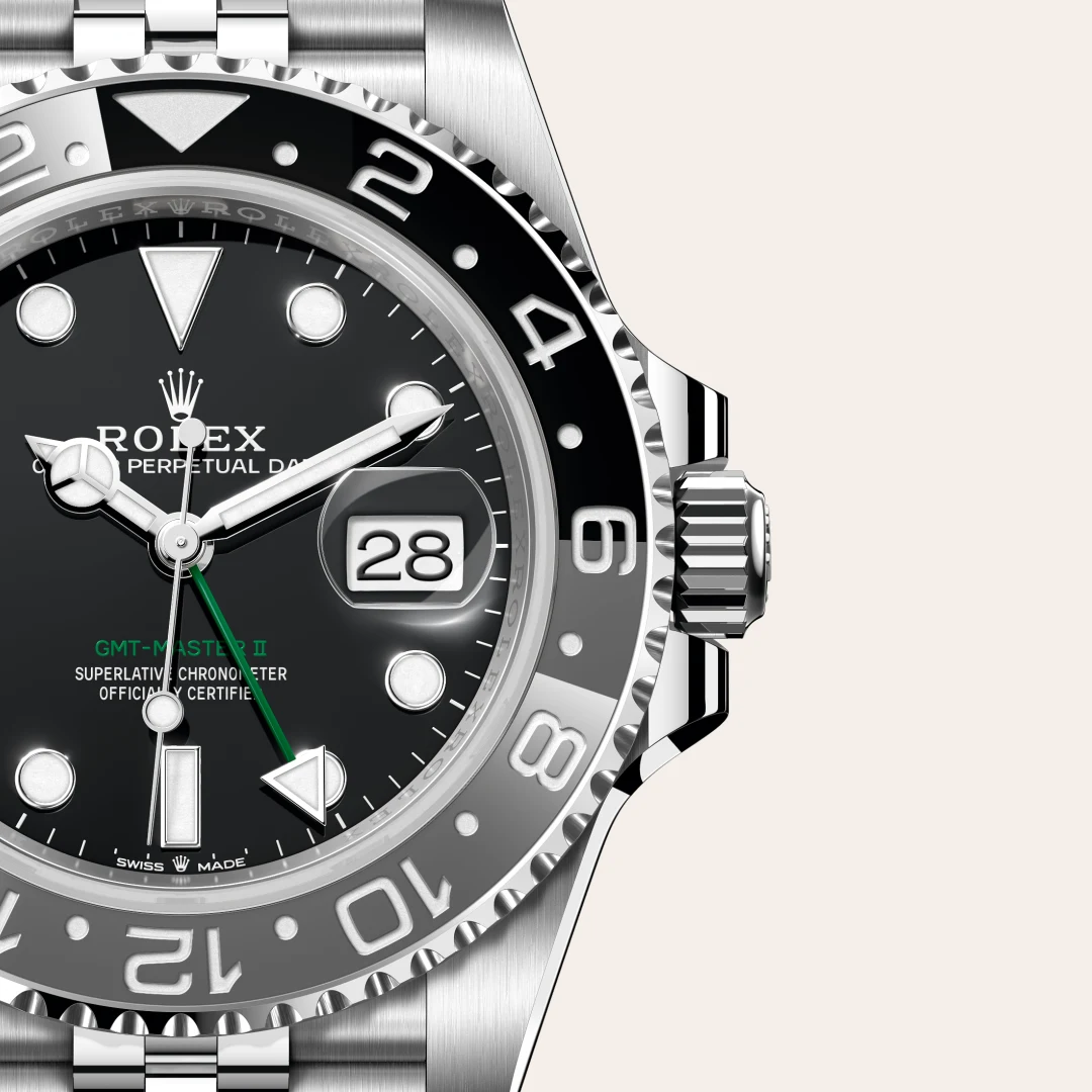 m126710grnr-0003-slide3 | Brela Close-up of a stainless steel Rolex GMT‑Master II watch with a black dial, date window at 3, green GMT hand, and a ridged bezel. | Brela