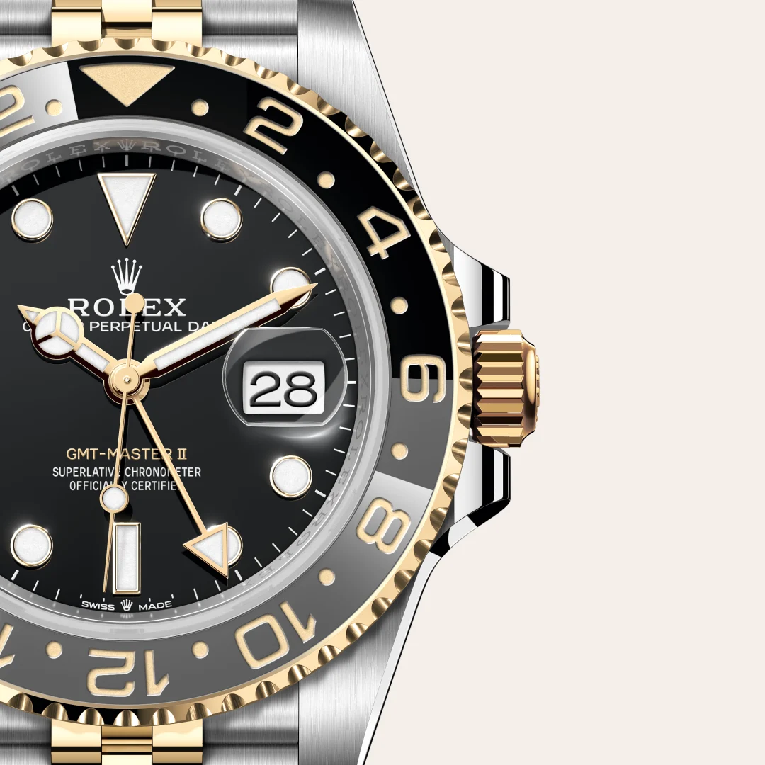m126713grnr-0001-slide3 | Brela Close-up of a two-tone gold and silver Rolex GMT-Master II watch face with date magnifier and black dial, showing brand and time indicators. | Brela