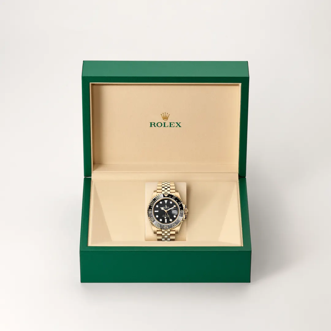 A gold Rolex wristwatch on a beige cushion inside an open green Rolex box. | Brela