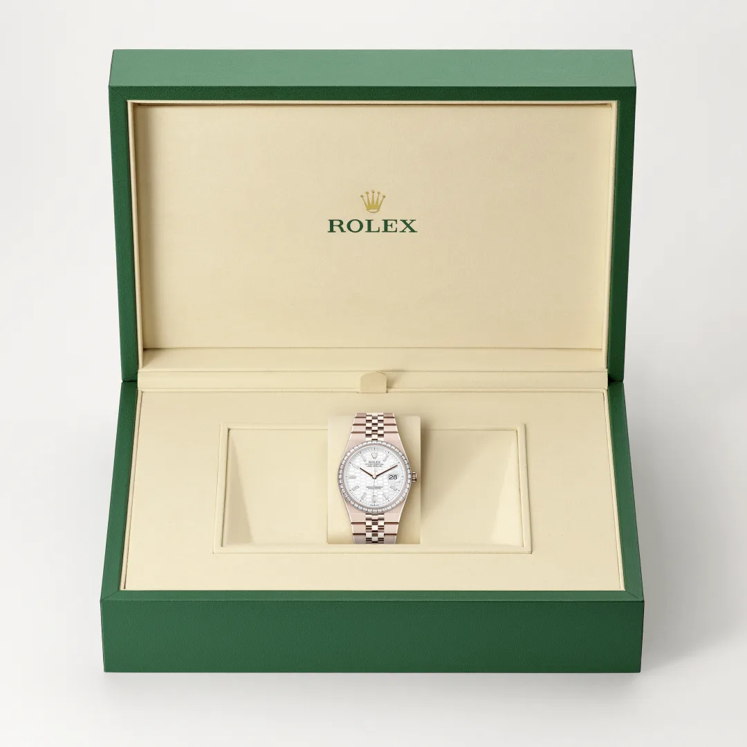 m127285tbr-0002-slide2 | Brela Rolex watch displayed in an open green box with a beige interior; the timepiece sits on a cushion in the center. | Brela