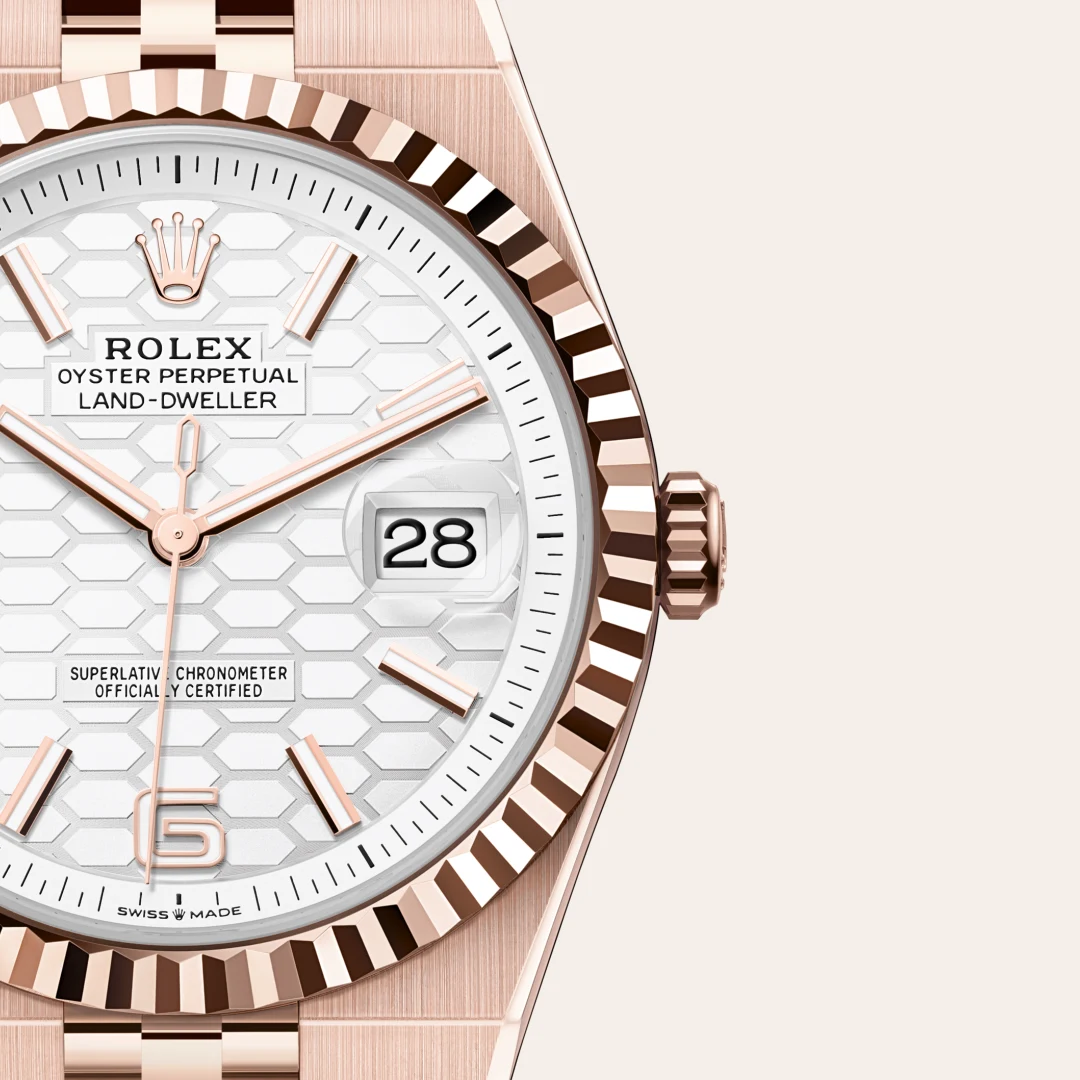 m127335-0001-slide3 | Brela Close-up of a rose-gold Rolex Oyster Perpetual Datejust watch with a white hexagonal-pattern dial, date window showing 28, and fluted bezel. | Brela