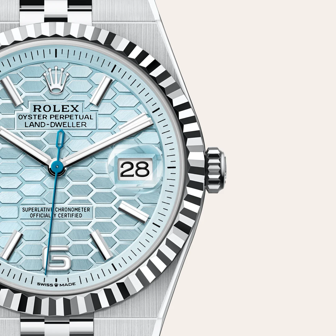 m127336-0001-slide3 | Brela Close-up of a Rolex Oyster Perpetual Land-Dweller watch with a light blue hexagonal dial, date window at 3, and a silver fluted bezel. | Brela