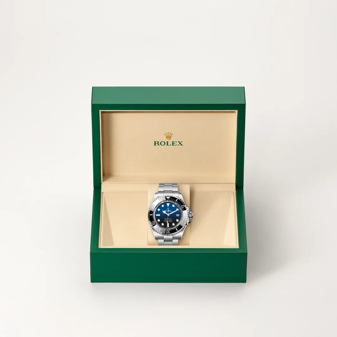 m136660-0005-slide2 | Brela Rolex watch with blue dial in a green presentation box with beige interior, showcasing the timepiece on a cushion | Brela