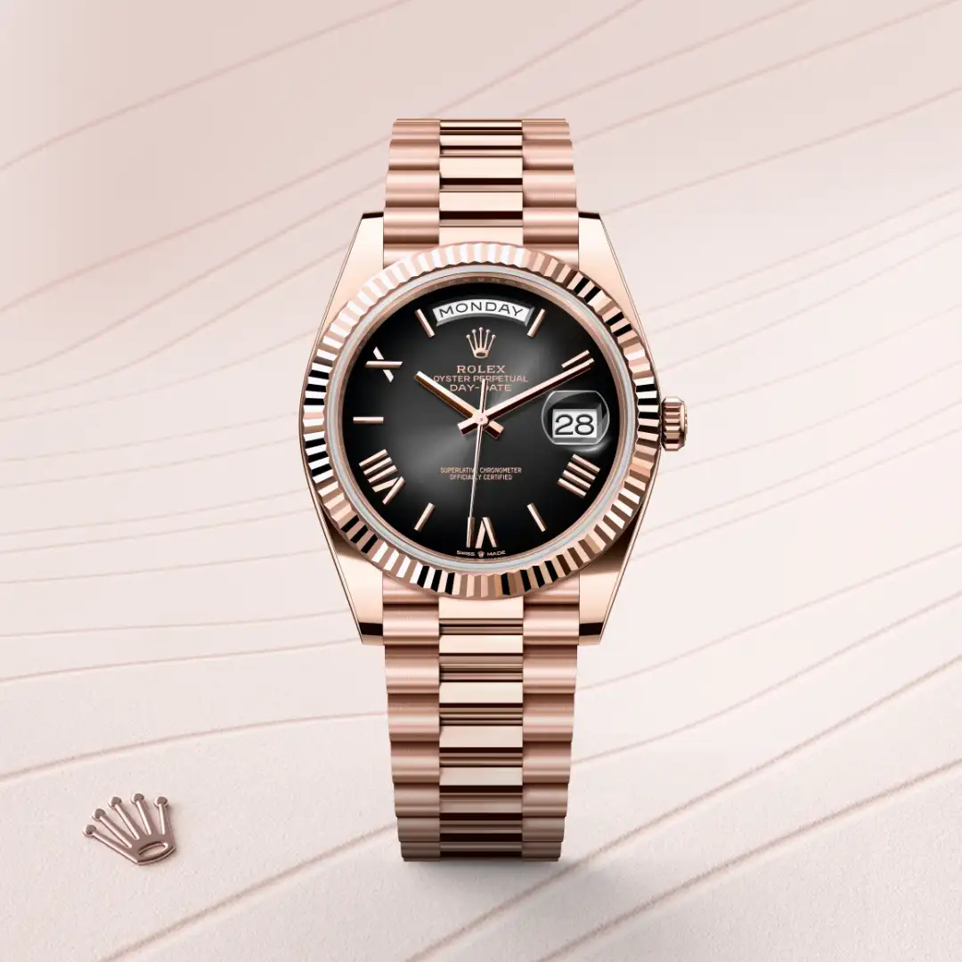 m228235-0055-slide1 | Brela Rose gold Rolex Day-Date watch with a black dial, fluted bezel, and linked bracelet on a pale pink background. | Brela
