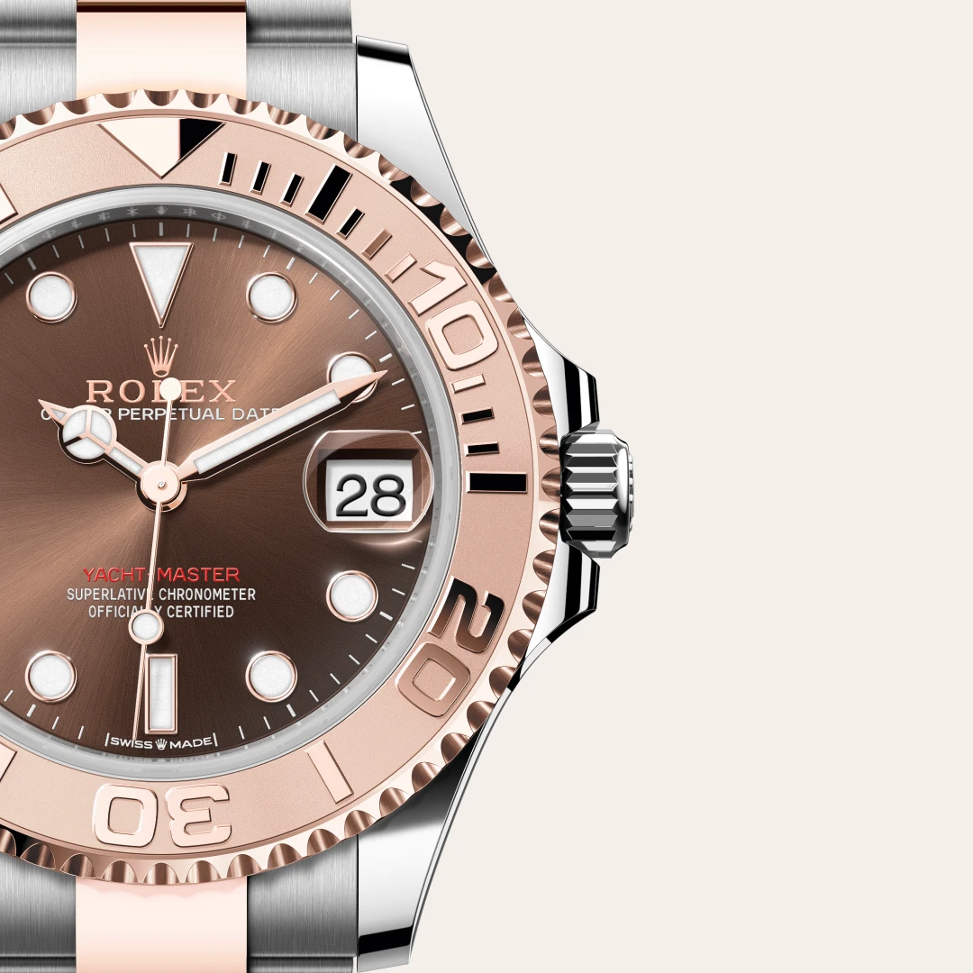 Close-up of a Rolex Yacht-Master watch with rose-gold bezel and brown dial, date window magnified at 3 o'clock, and two-tone bracelet. | Brela