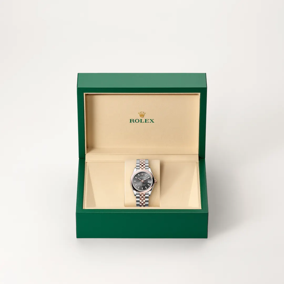 Green Rolex watch box opened to reveal a two-tone silver and gold Rolex watch with a dark dial and date window inside a beige interior | Brela