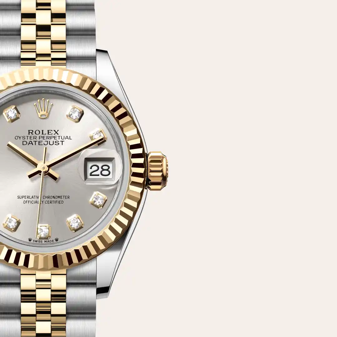 m279173-0007-slide3 | Brela Close-up of a two-tone gold and steel Rolex Datejust, showing fluted bezel, diamond hour markers, and date window set to 28 (Swiss Made). | Brela
