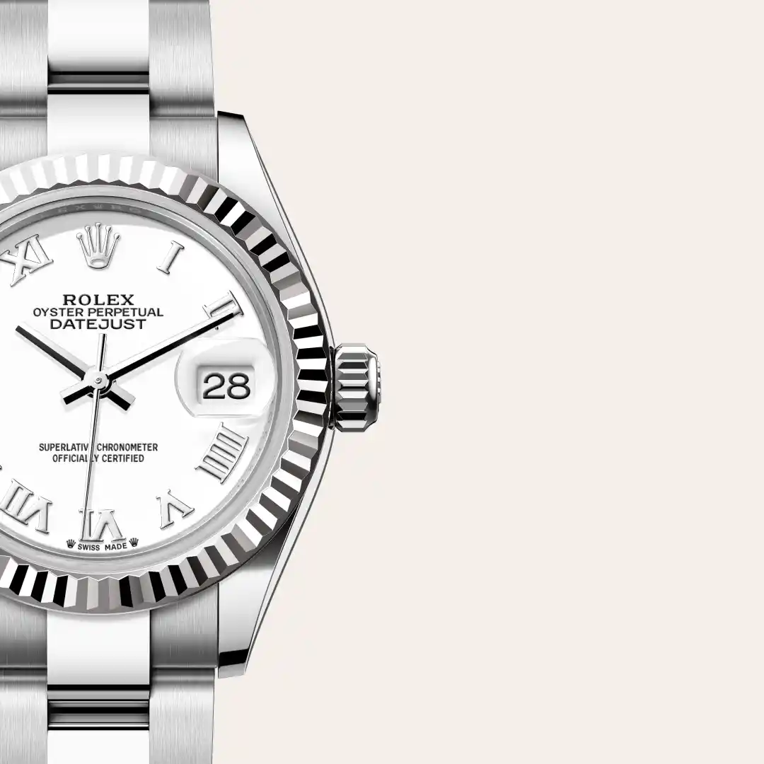 Close-up of a silver Rolex Oyster Perpetual Datejust wristwatch with a fluted bezel, white dial, Roman numerals, and a date window showing 28; metal bracelet visible. | Brela
