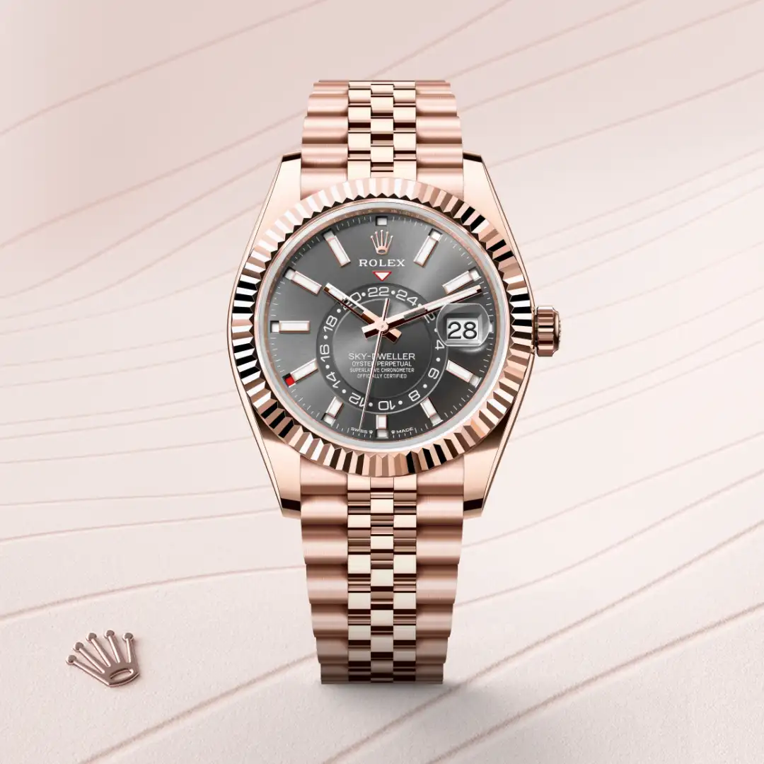 Rose gold Rolex Sky-Dweller watch with a gray dial, fluted bezel, and Jubilee bracelet on a light backdrop. | Brela