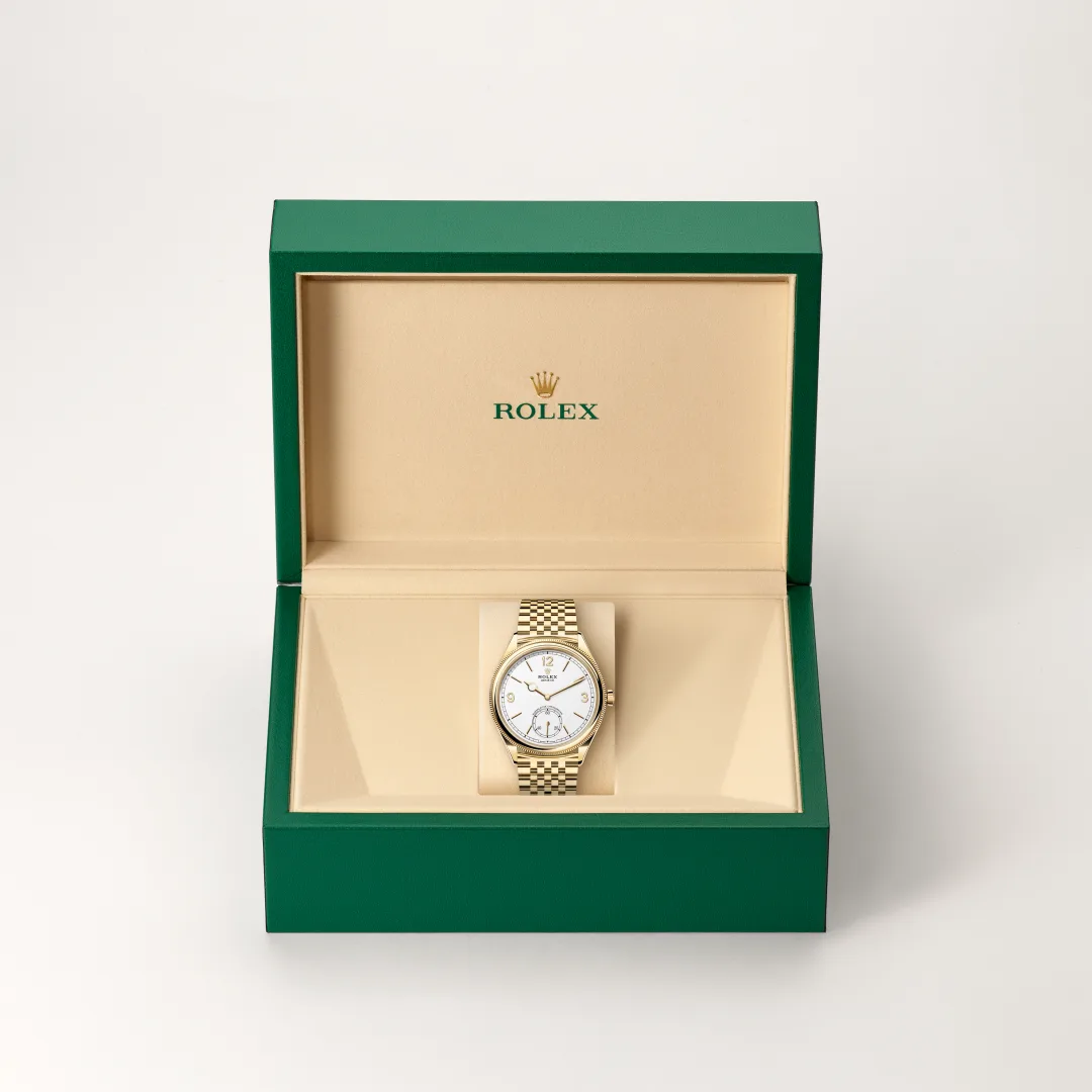 m52508-0008-slide2 | Brela Gold-tone Rolex wristwatch with white dial displayed in an open green presentation box, showing the Rolex logo inside. | Brela
