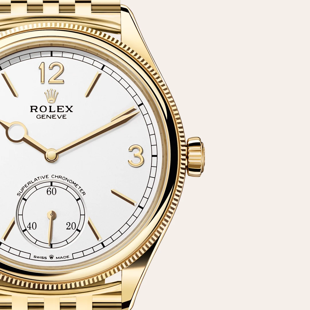 m52508-0008-slide3 | Brela Close-up of a gold Rolex wristwatch with a white dial, crown logo, and subdial, showing 12 and 3 numerals, Swiss made | Brela