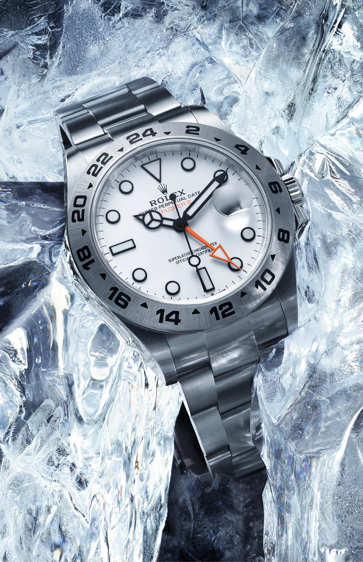 Rolex Explorer II wristwatch with white dial, orange 24-hour hand, and stainless steel bracelet resting on ice.