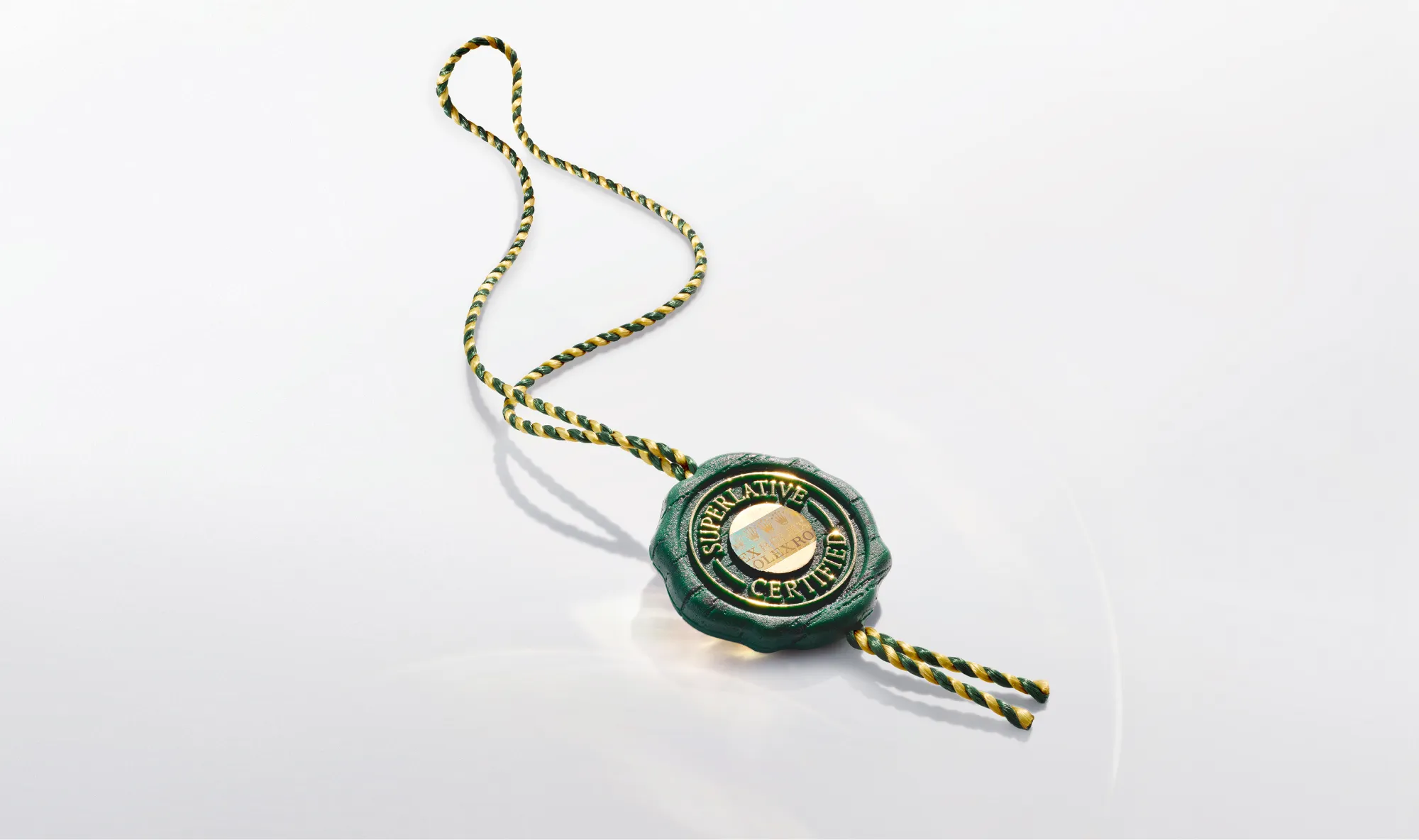 Close-up of a green wax seal with a gold inner emblem, attached to a green-and-gold braided cord