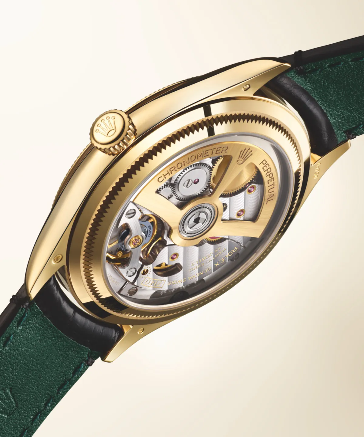rolex-perpetual-1908-m52508-0002_2301uf_002-landscape Close-up of a gold Rolex wristwatch showing its intricate mechanical movement through a transparent caseback, with a green strap visible on the side.