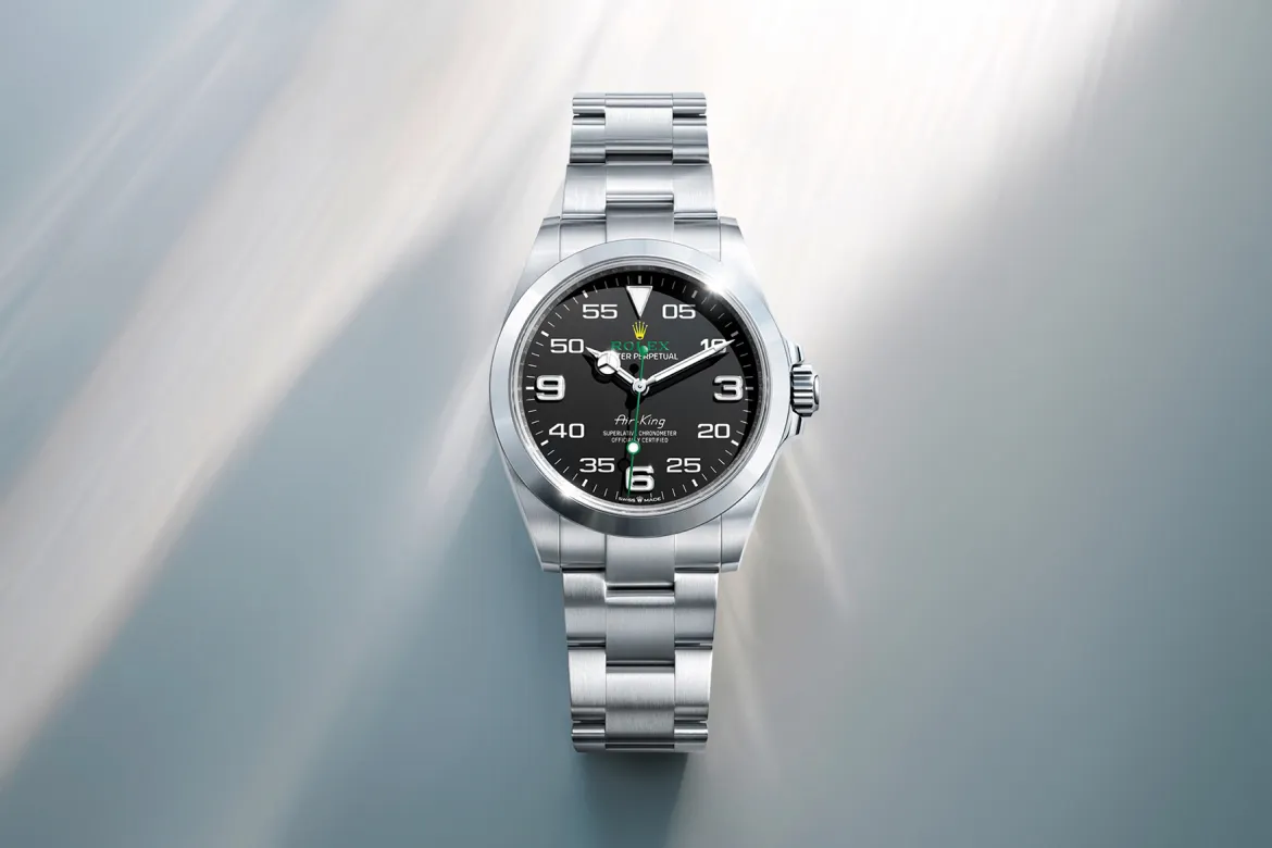 rolex-watches-air-king-m126900-0001-landscape | Brela Rolex Air-King stainless steel watch with a black dial and silver bezel, resting on a soft blue background | Brela
