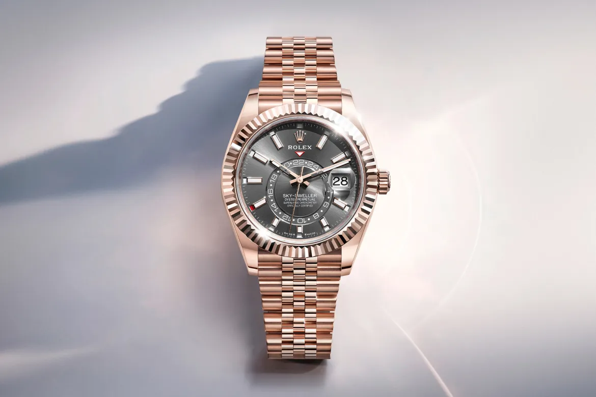 rolex-watches-sky-dweller-m336935-0008-landscape | Brela Rose gold Rolex Sky-Dweller wristwatch with grey dial, fluted bezel, and date window magnifier on a light background | Brela