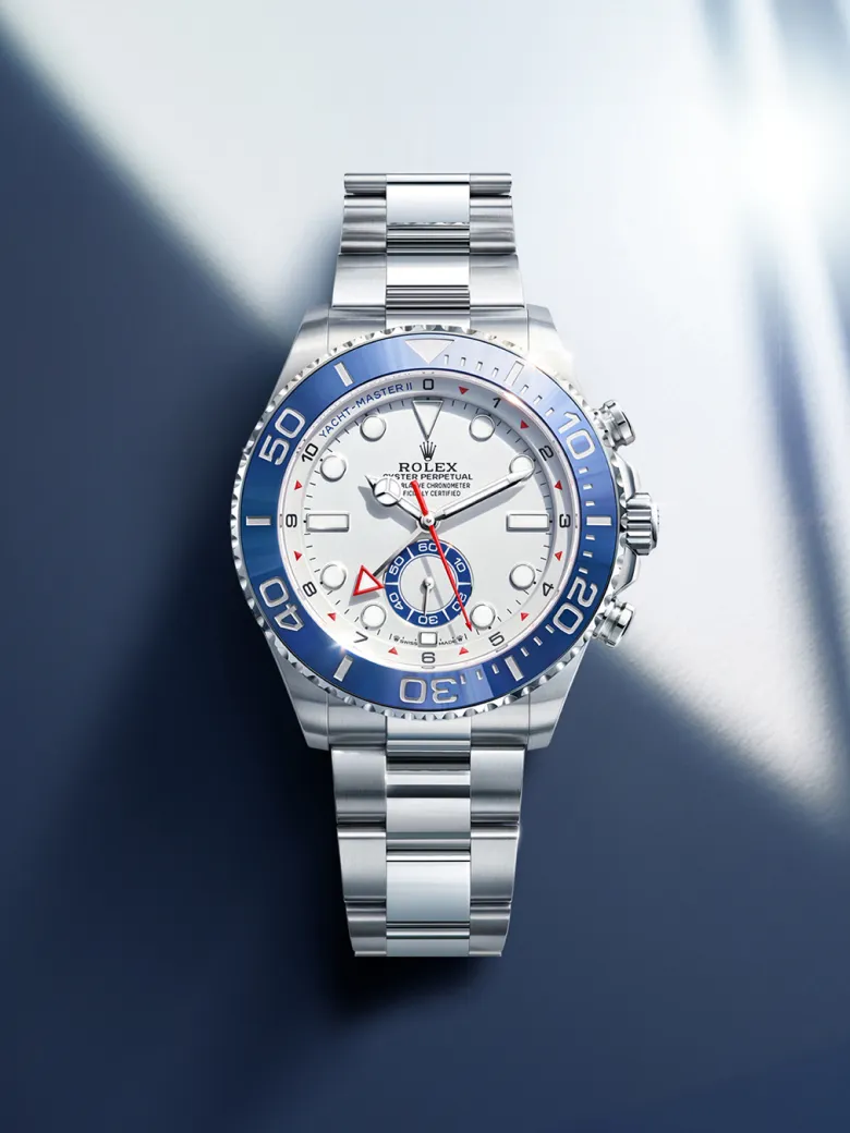 rolex-watches-yacht-master-ii-m126680-0001-portrait | Brela Silver Rolex wristwatch with a blue bezel and white dial on a blue background, close-up view. | Brela