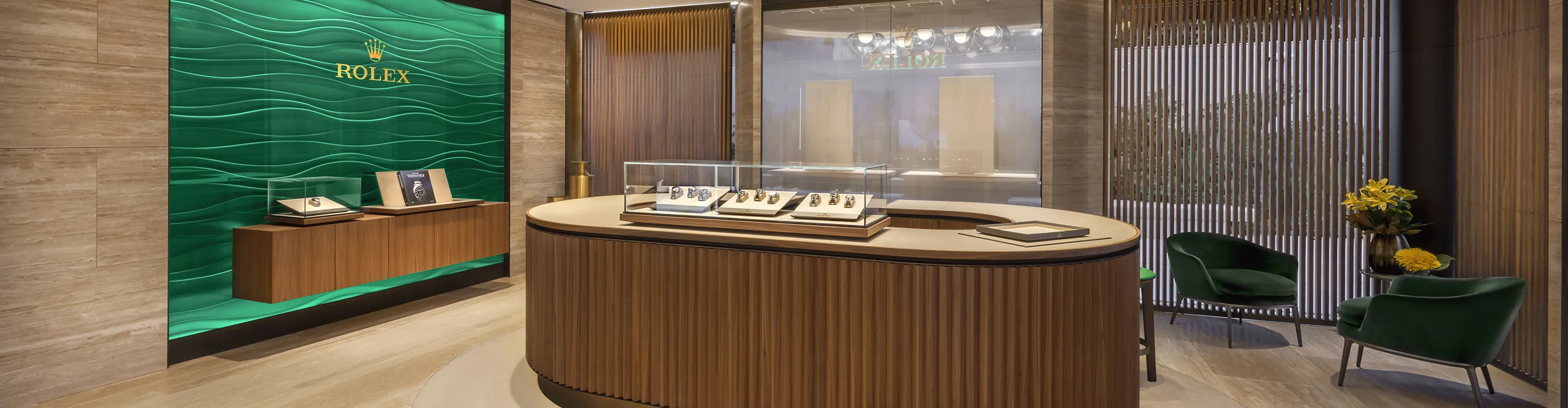 Brela-carrasco | Brela Luxurious Rolex showroom interior with a curved wooden display counter, glass watch case, and a green wave-textured wall with seating area. | Brela