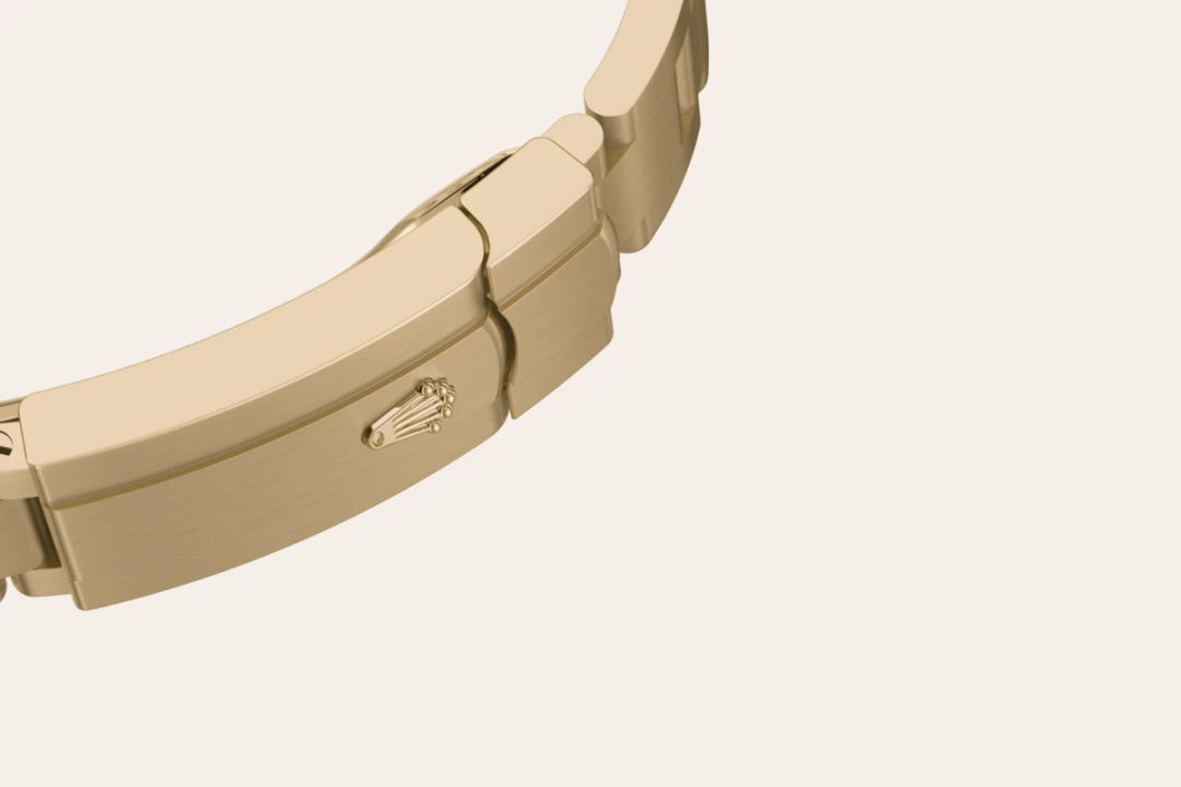 m124208-0001-bracelet-landscape | Brela Gold metal Rolex watch bracelet curved along a pale background, with the Rolex crown logo on the clasp. | Brela