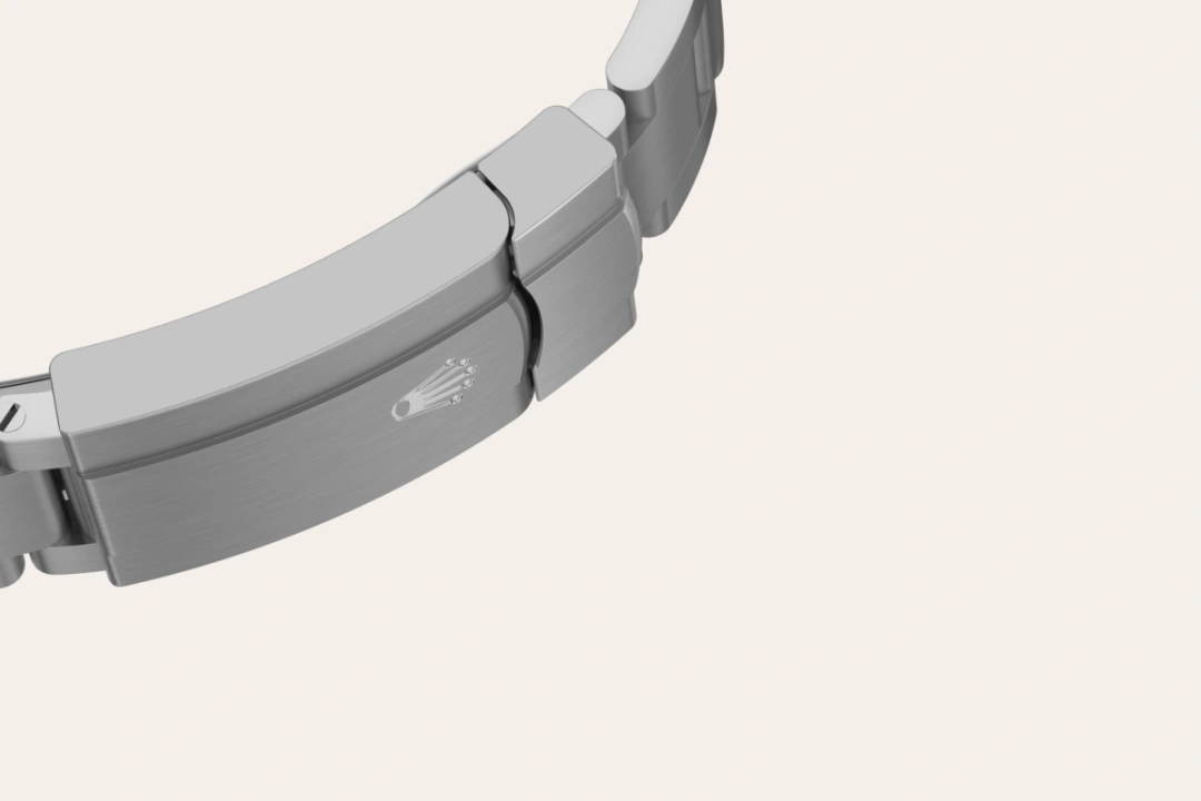 m126000-0014-bracelet-landscape | Brela Close-up of a brushed metal watch bracelet clasp with a small crown emblem on the band | Brela