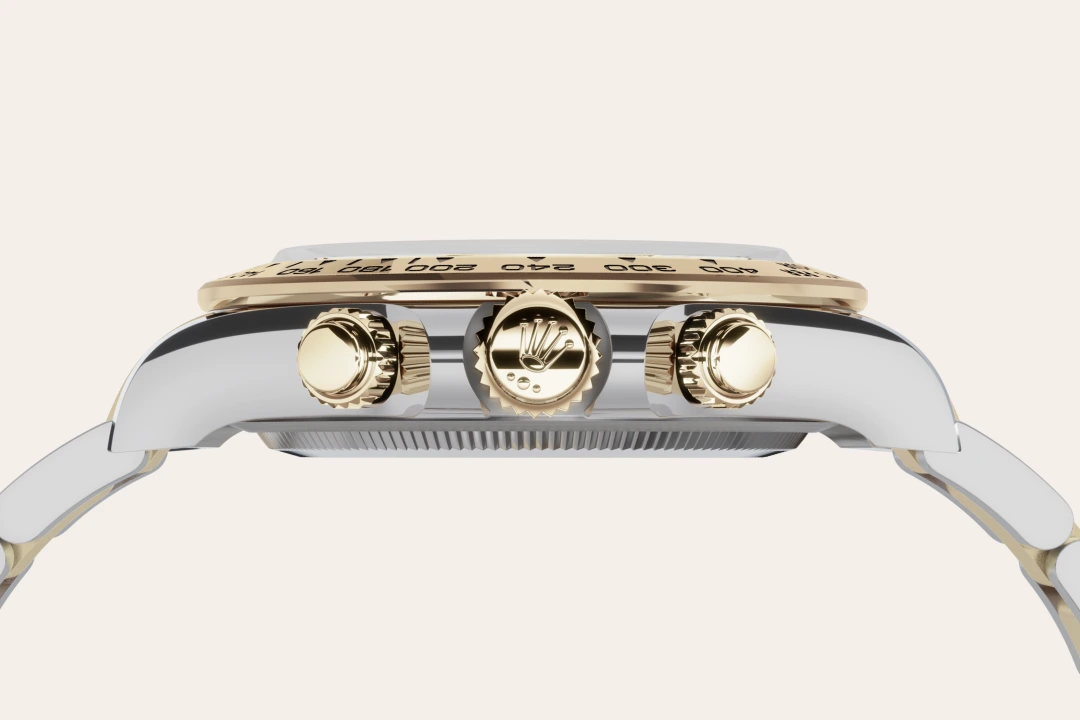 Close-up side view of a two-tone luxury wristwatch, featuring the crown and two pushers with the Rolex logo on the center crown.