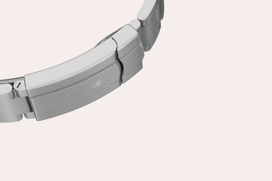 Close-up of a stainless steel watch bracelet clasp with a small Rolex crown logo. | Brela