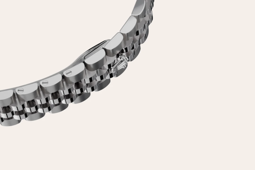 Close-up of a silver stainless steel watch bracelet curving across a light background. | Brela